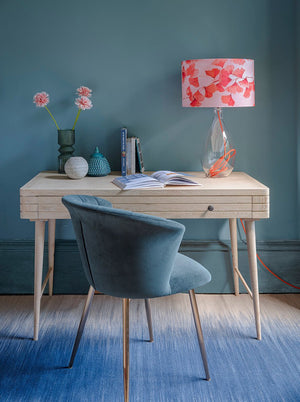 Glass lamp base with clementine orange flex by Anna Jacobs, shown in a home office lifestyle setting with Ginkgo in Coral lampshade
