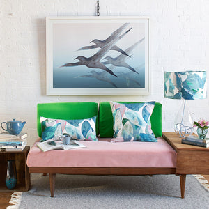 Anna Jacobs Falling leaves in Winter linen bolster lifestyle image on sofa with lamp and Breathe print on wall